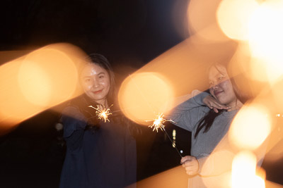 Two girls playing around with the light sticks in the night.